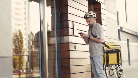 Food-Delivery-Man-Wearing-Thermal-Backpack-Calls-The-Entry-Phone-Of-A-Building-To-Make-A-Delivery