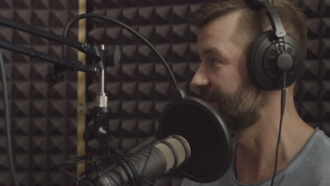 A-Radio-Presenter-With-A-Beard-Speaks-Through-The-Microphone-In-A-Radio-Studio