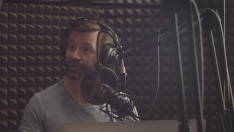 Happy-Radio-Broadcaster-With-A-Beard-Speaks-To-The-Microphone-In-A-Radio-Studio