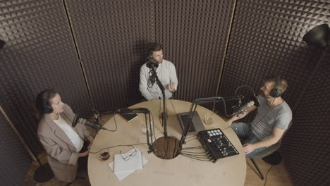 Top-View-General-Shot-Of-Three-People-Having-A-Conversation-In-A-Radio-Recording-Studio