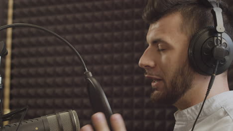 Close-Up-Of-A-Young-Radio-Presenter-With-Beard-And-Braces-Speaking-Into-The-Microphone-In-A-Recording-Studio