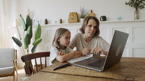 Mutter-Erklärt-Ihrer-Hübschen-Blonden-Tochter-Den-Unterricht-über-Den-Laptop-bildschirm