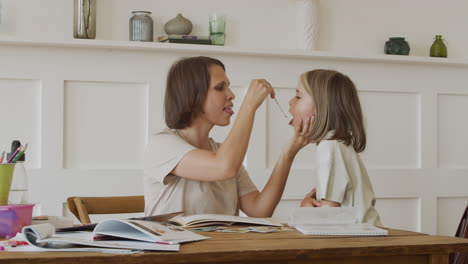 Eine-Mutter-Macht-Mit-Ihrer-Tochter-Hausaufgaben-Und-Legt-Ihr-Ein-Metallgerät-Auf-Die-Zunge,-Damit-Sie-Versteht,-Wie-Geschmacksknospen-Funktionieren