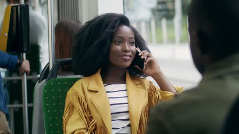 Beautiful-Young-Girl-With-Curly-Hair-Sitting-In-The-Tram-And-Talking-Cheerfully-On-The-Mobile-Phone