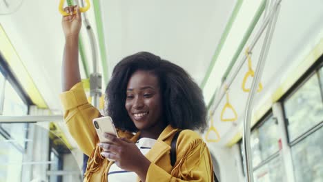 Close-Up-Of-The-Young-Smiled-Pretty-Girl-Standing-In-The-Tram-While-Going-Somewhere-And-Chatting-With-Messages-On-The-Mobile-Phone