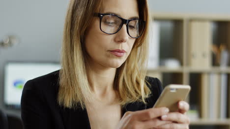 Nahaufnahme-Der-Vielbeschäftigten-Schönen-Geschäftsfrau-Mit-Brille,-Die-Im-Büro-Auf-Ihrem-Smartphone-Aufzeichnet-Und-Sms-Schreibt