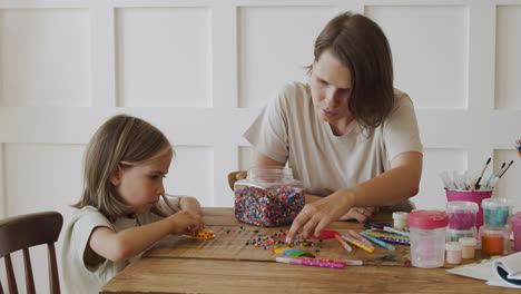 A-Little-Blonde-Girl-And-Her-Mother-Playing-With-Colored-Beads
