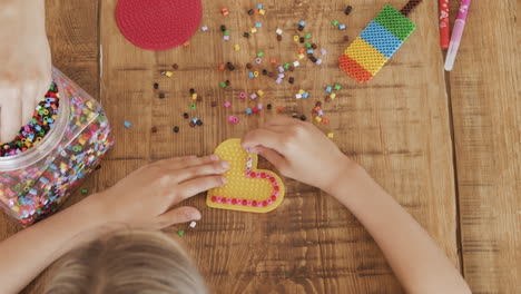 Close-Up-Top-Shot-Of-The-Hands-Of-A-Little-Girl-And-Her-Mother-Playing-With-Colored-Beads