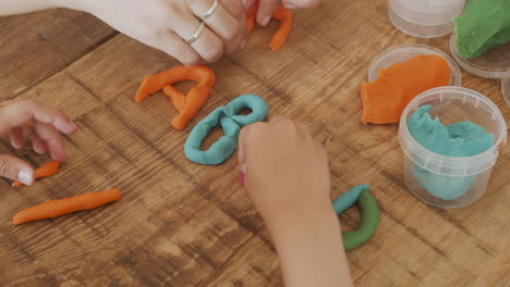 Detail-Shot-Of-A-Girl's-Hands-Playing-With-Play-Dough-And-Creating-Colored-Letters