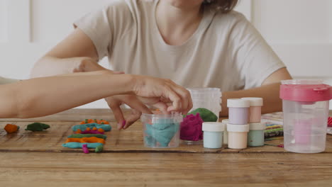 Close-Up-Detail-Of-The-Hands-Of-A-Woman-And-Her-Daughter-Modeling-Letters-With-Colored-Plasticine