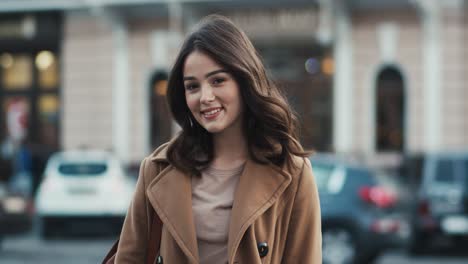 Portrait-Of-A-Beautiful-Brunette-Girl-Smiling-At-The-Camera-While-City-Traffic-Circles-Behind-Her