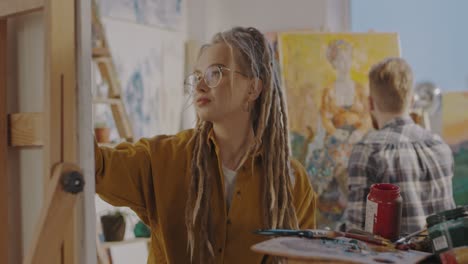 Portrait-Of-Young-Pretty-Stylsih-Hipster-Female-Artist-With-Dreadlocks-And-In-Glasses
