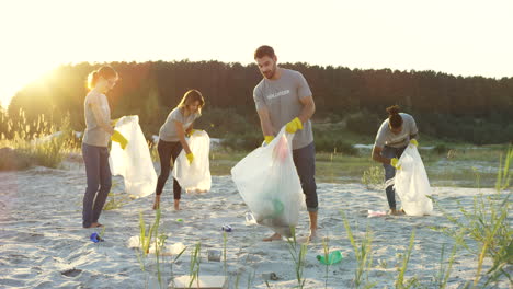 Young-Team-Of-Multiethnical-Volunteers-Cleaning-Up-The-Beach-At-The-Lake