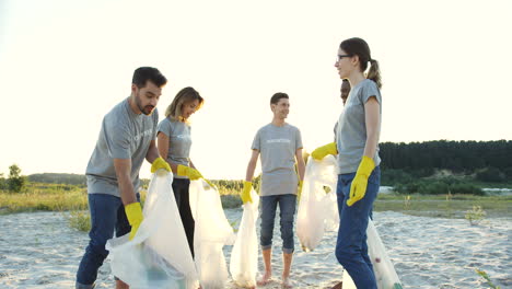 Gemischte-Rassen,-Die-Sich-Freiwillig-Am-Strand-Melden-Und-Emotional-Reden,-Während-Sie-Müll-Aufsammeln-Und-Ihn-In-Die-Plastiktüten-Werfen