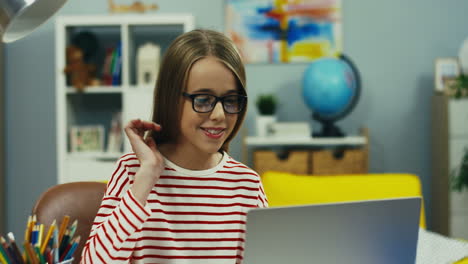 Hübsches-Teenager-Mädchen-Mit-Brille,-Das-Mit-Einem-Laptop-Am-Schreibtisch-Sitzt-Und-Zu-Hause-Per-Webcam-Per-Videochat-Chattet