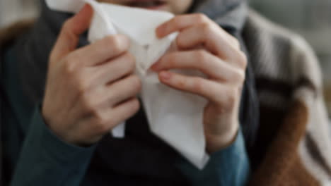 Close-Up-Of-The-Young-Unhealthy-Woman-In-The-Warm-Scarf-And-A-Plaid-Blowing-Her-Nose-In-The-Napkin-As-She-Having-A-Cold