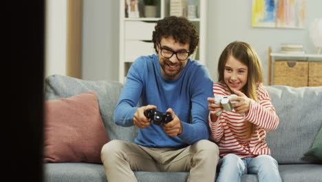 Fröhlicher-Vater,-Der-Zusammen-Mit-Seiner-Süßen-Tochter-Emotional-Videospiele-Spielt