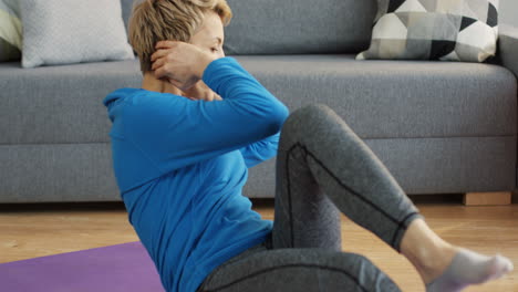 Sportliche-Blonde-Frau-Mittleren-Alters-Trainiert-Ihre-Bauchmuskeln-Auf-Der-Yogamatte-Zu-Hause