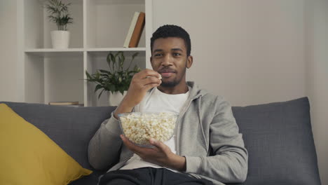 Young-Man-Enjoying-A-Movie-And-Eating-Popcorn