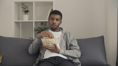 Young-Male-Looking-Directly-At-The-Camera-And-Showing-Us-A-Popcorn