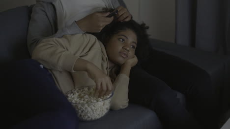 Young-Woman-Watching-A-Movie-And-Eating-Popcorn-Leaning-On-Her-Boyfriend's-Lap