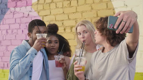 Group-Of--Young-Friends-Taking-Selfies-Together-And-Having-Fun-Outdoors,-While-Holding-And-Drinking-Fresh-Drinks-In-Plastic-Cups