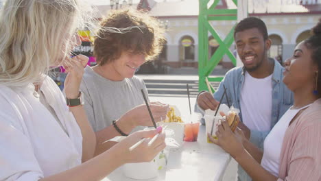 Group-Of-Cheerful-Multiethnic-Friends-Eating-Street-Food-In-The-City-While-Chatting-And-Spending-Time-Together