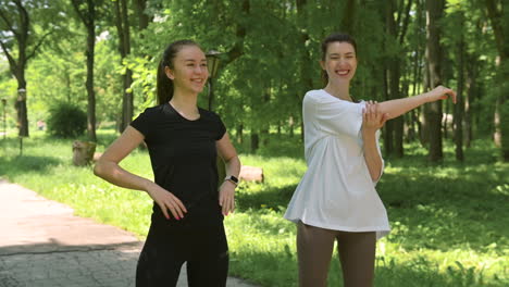 Two-Happy-Pretty-Girl-Runners-Warming-Up-And-Stretching-In-The-Park-Before-Running