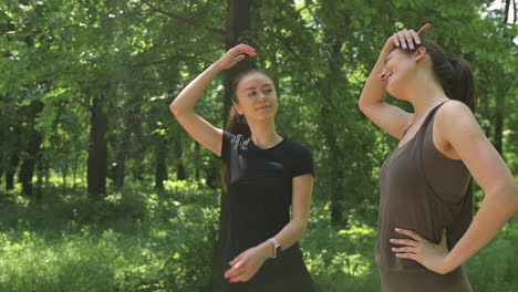 Two-Pretty-Girl-Runners-Warming-Up-And-Streching-Their-Necks-In-The-Park
