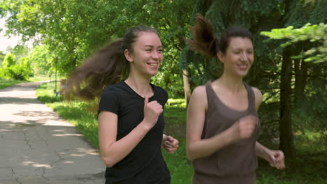 Zwei-Hübsche-Sportlerinnen,-Die-Draußen-Im-Park-Laufen