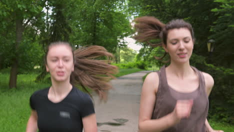 Two-Pretty-Sportswomen-With-Ponytail-Running-Outdoors,-In-The-Park