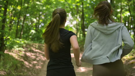 Back-View-Of-Two-Happy-Sportswomen-Running-In-The-Woods