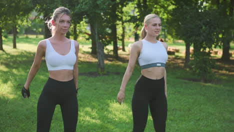 Two-Beautiful-Blonde-Sporty-Women-Doing-Squats-In-The-Park
