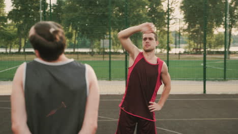 Two-Male-Basketball-Players-Stretching-In-An-Outdoor-Basketball-Court-Before-Playing