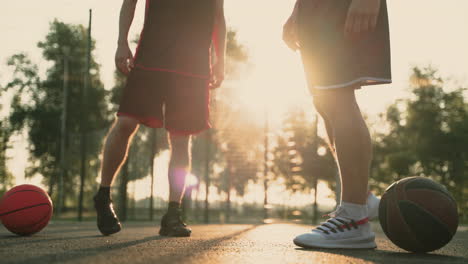 Close-Up-Of-Two-Basketball-Players-Stretching-Their-Ankles,-In-An-Outdoor-Baskeball-Court
