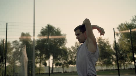 Concentrated-Sportsman-Doing-Tricep-Stretch-Exercises-In-Outdoor-Court-At-Sunset