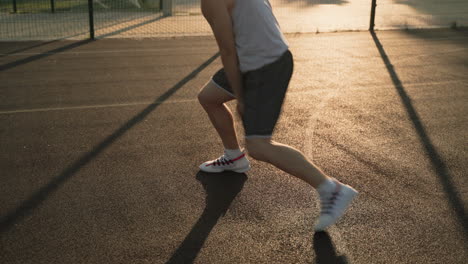 A-Male-Basketball-Player-Bouncing-And-Dribbling-The-Ball-Between-His-Legs-In-An-Outdoor-Court-At-Sunset-1