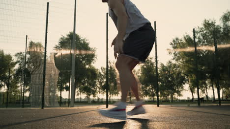 Jugador-De-Baloncesto-Masculino-Rebotando-La-Pelota,-Regateando-Y-Haciendo-Movimientos-Giratorios-En-Una-Cancha-Al-Aire-Libre-Al-Atardecer