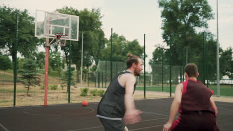 A-Skillfull-Basketball-Player-Dribbling-The-Ball-Between-The-Legs-Against-His-Opposing-Defender-And-Throwing-Ball-Into-Outdoor-Basketball-Hoop