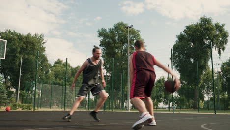A-Skillfull-Basketball-Player-Dribbling-The-Ball-Between-The-Legs-Against-His-Opposing-Defender-And-Throwing-Ball-Into-Outdoor-Basketball-Hoop-1