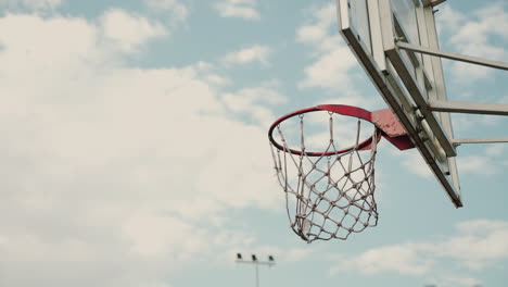 Close-Up-Of-Outdoor-Basketball-Hoop-In-A-Sunny-Day,-While-An-Unknown-Person-Throwing-Ball-Into-Basketball-Ring-Four-Times-Successfully