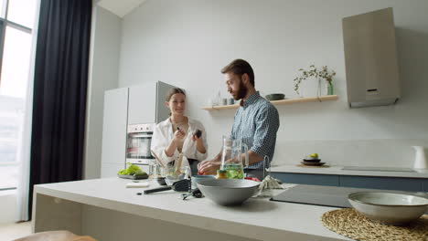 Fröhliches-Junges-Paar,-Das-Gemeinsam-Salat-In-Einer-Modernen-Küche-Zubereitet