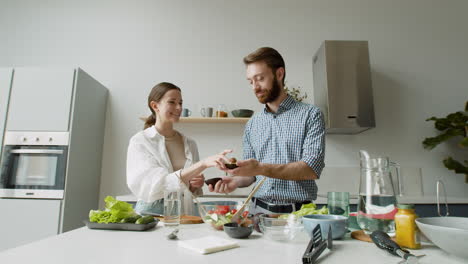 Fröhliches-Junges-Paar,-Das-Gemeinsam-Salat-In-Einer-Modernen-Küche-Zubereitet-1