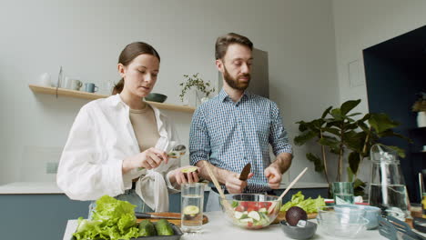 Fröhliches-Junges-Paar,-Das-Gemeinsam-Salat-In-Einer-Modernen-Küche-Zubereitet-2
