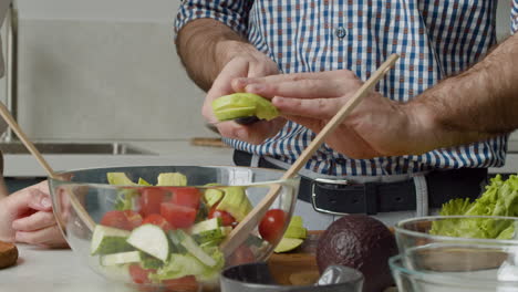 Nahaufnahme-Von-Menschenhänden,-Die-Avocadoscheiben-In-Eine-Glasschüssel-Geben,-Um-Einen-Gesunden-Und-Leckeren-Salat-Zuzubereiten