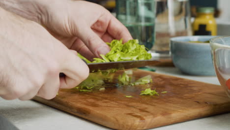 Nahaufnahme-Von-Menschenhänden,-Die-Salat-Schneiden-Und-In-Eine-Glasschüssel-Geben,-Um-Einen-Gesunden-Salat-Zuzubereiten