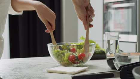 Close-Up-Of-Female-Hands-Adding-Various-Seeds-To-A-Delicious-Avocado-Salad-And-Mixing-It-In-A-Glass-Bowl-With-Wooden-Spatulas