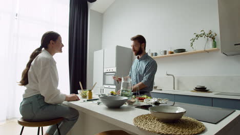 Cheerful-Couple-Chatting-And-Preparing-A-Tasty-Salad-In-A-Modern-Kitchen-1