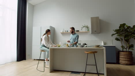 Cheerful-Couple-Chatting-About-Something-Funny-While-Preparing-A-Tasty-Salad-In-A-Modern-Kitchen