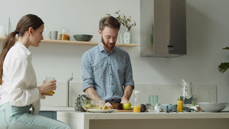 Happy-Couple-Chatting-And-Preparing-Lunch-Together-In-A-Modern-Kitchen